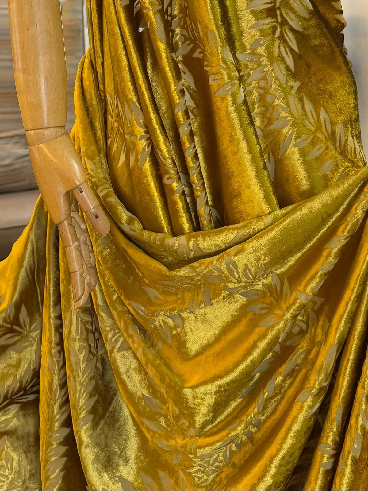Golden Italian velvet with intricate floral detailing draped over a mannequin in studio setting.