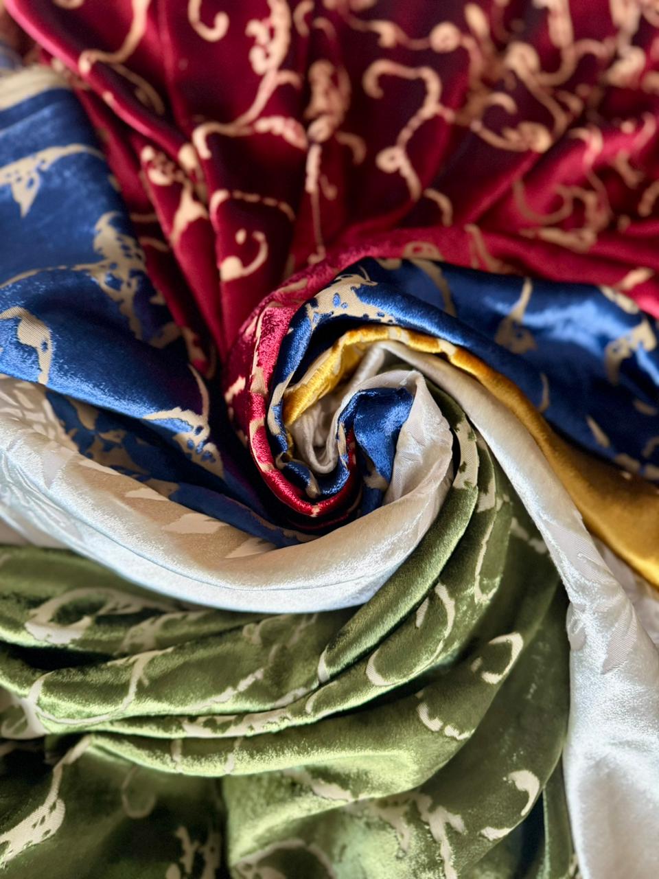 Rolled Italian velvet fabrics layered in red, blue and green tones inside Factory BCN.