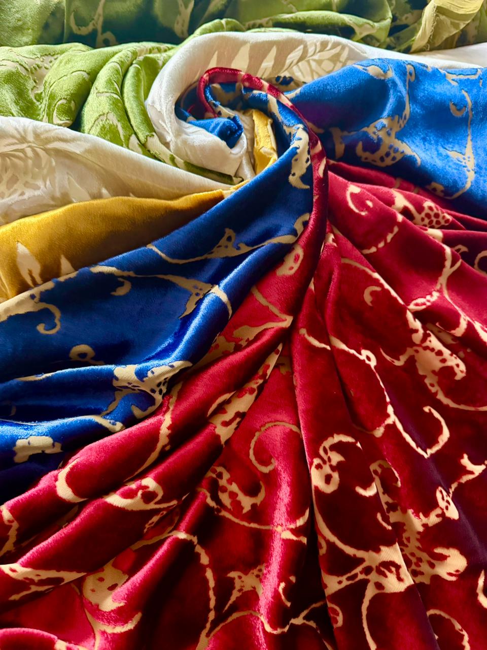 Red and blue velvet fabrics with gold pattern arranged in layered composition