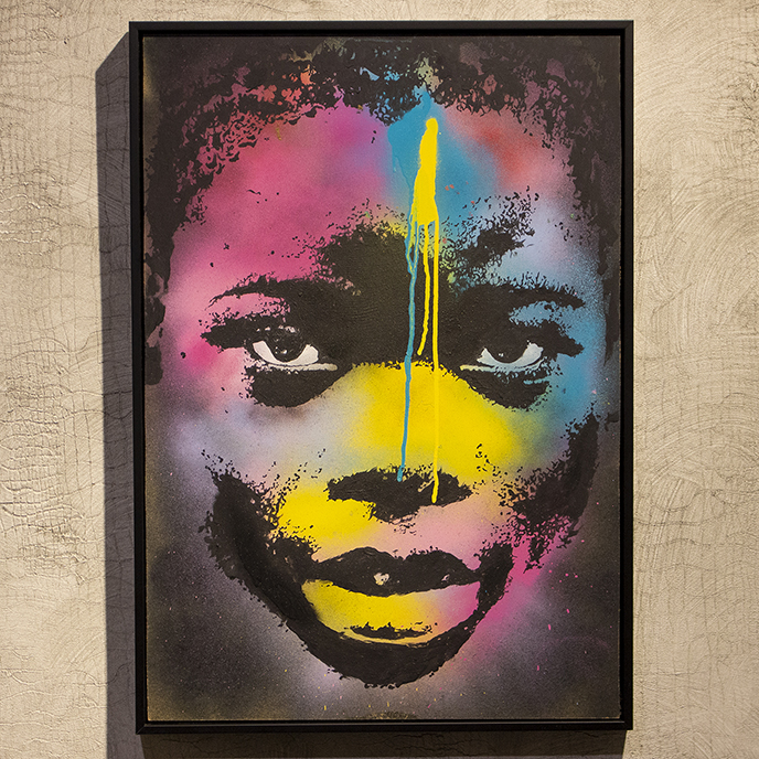 Portrait of an African child by Riccardo Lopez with black and white facial features surrounded by pink, blue and yellow paint