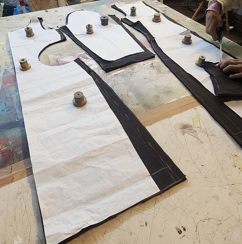 Black technical fabric pattern pieces pinned on a cutting table for garment construction