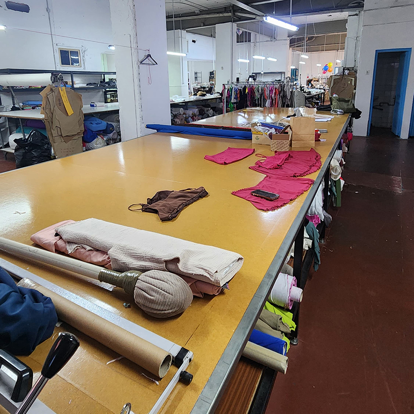 Cutting table with fabric rolls and pink fabric pieces prepared for garment production