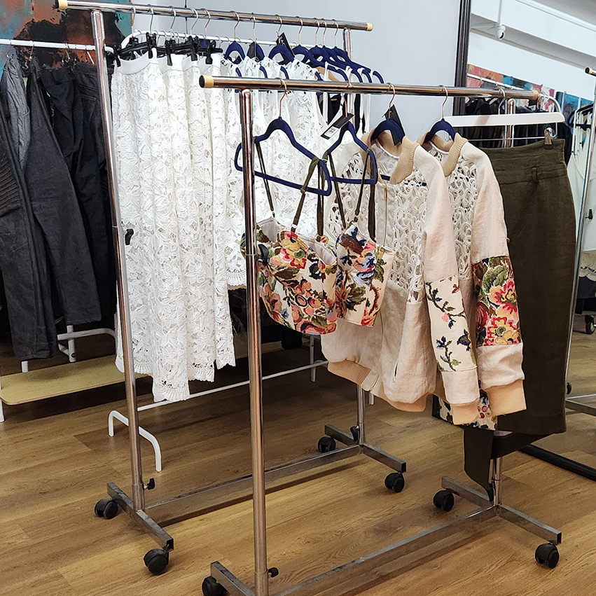 Clothing rack with white lace garments and floral embroidered jackets from finished collection