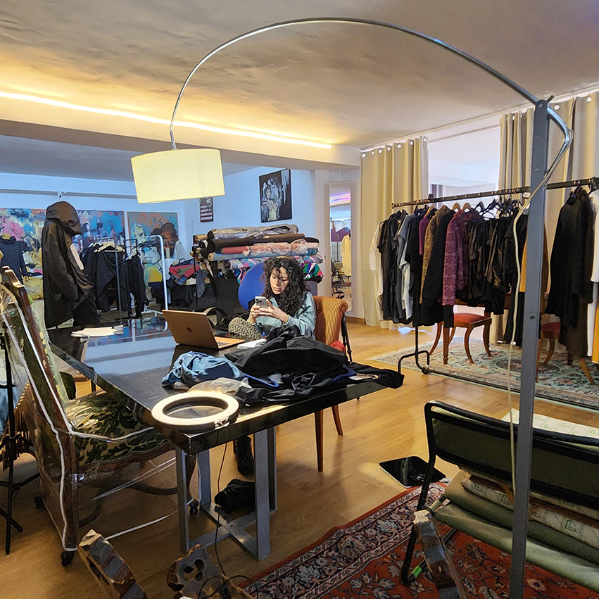 Fashion design studio workspace with desk, ring light and clothing racks in Barcelona